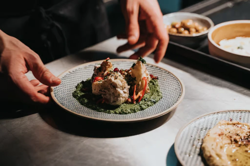 Anrettet ret med grøn sauce, der gøres klar til servering